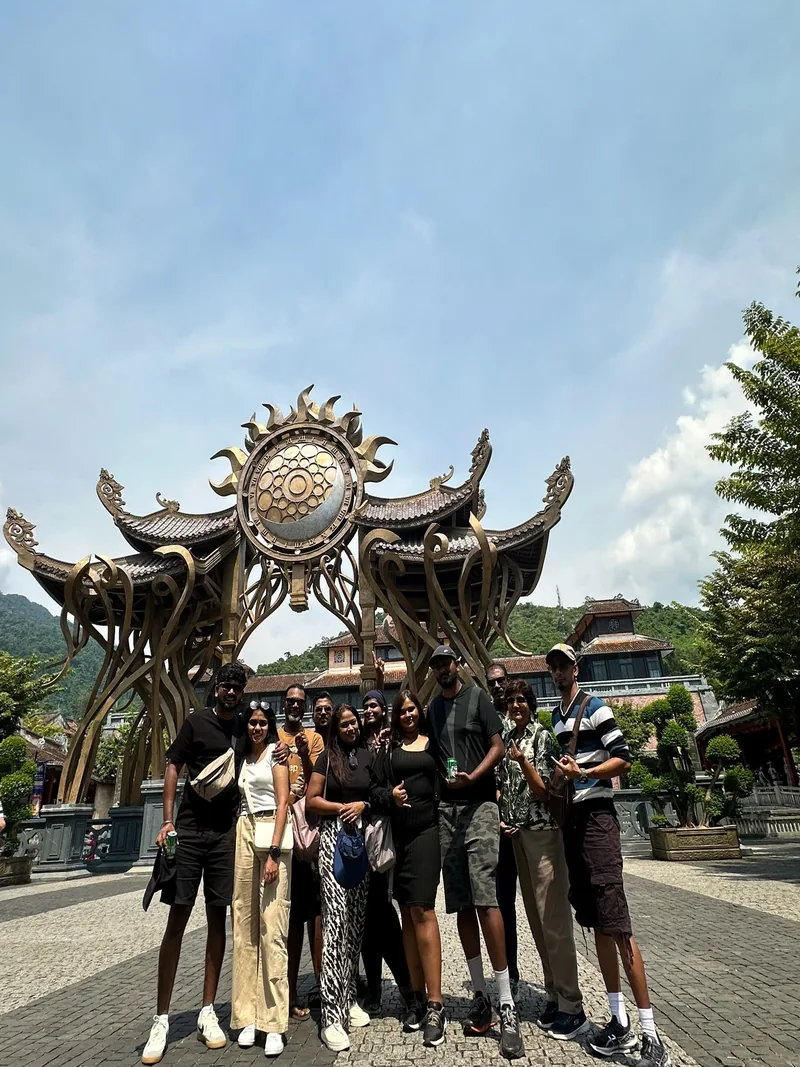 Large group of friends at Ba Na Hills French Village ornate clock sculpture — group day trip from Hoi An by private van