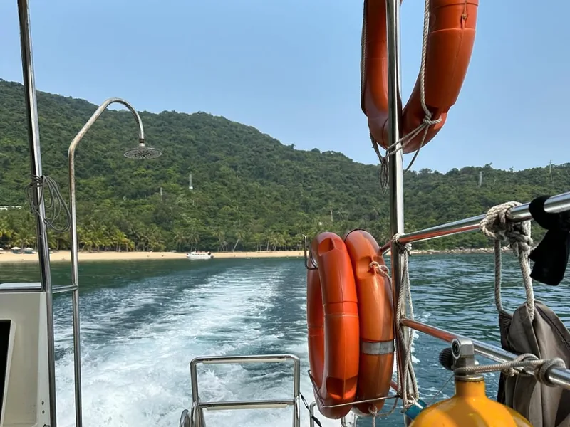 View from the back of a diving boat leaving Cham Islands — scuba tank and life ring visible — Cu Lao Cham in background