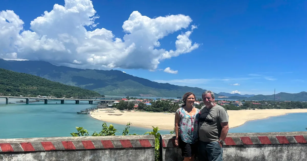 Couple at Hai Van Pass summit viewpoint — Lang Co bay and lagoon behind — Hoi An to Hue scenic route by private car — Minh Vu Travel