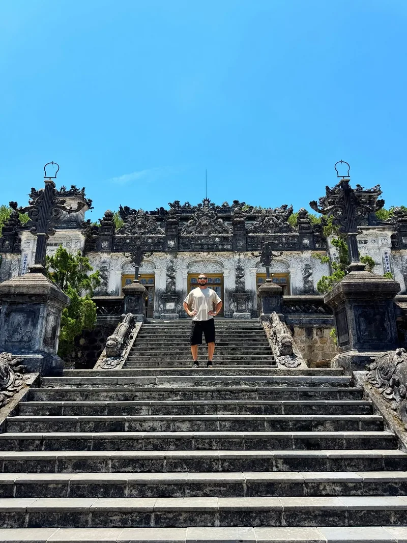Visitor at Khai Dinh Tomb steps in Hue — ornate grey stone structure blending Vietnamese and European architecture — day trip from Hoi An
