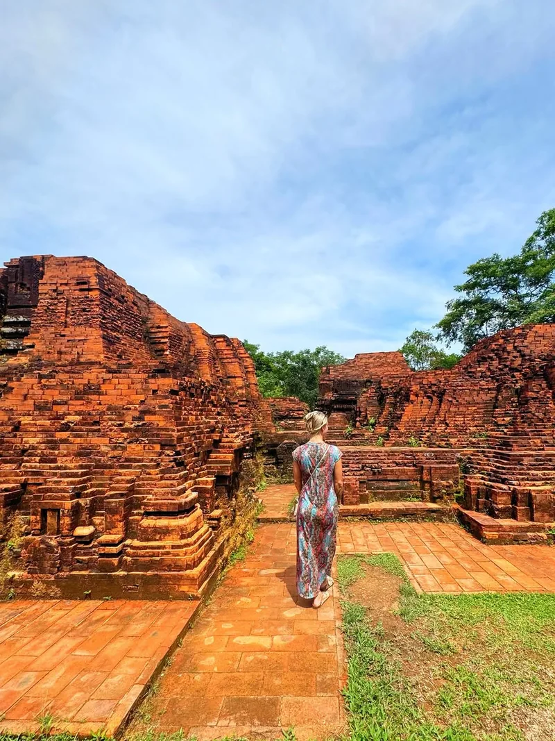 Woman walking among 4th-century Cham brick towers at My Son Sanctuary — UNESCO World Heritage site 45 km from Hoi An