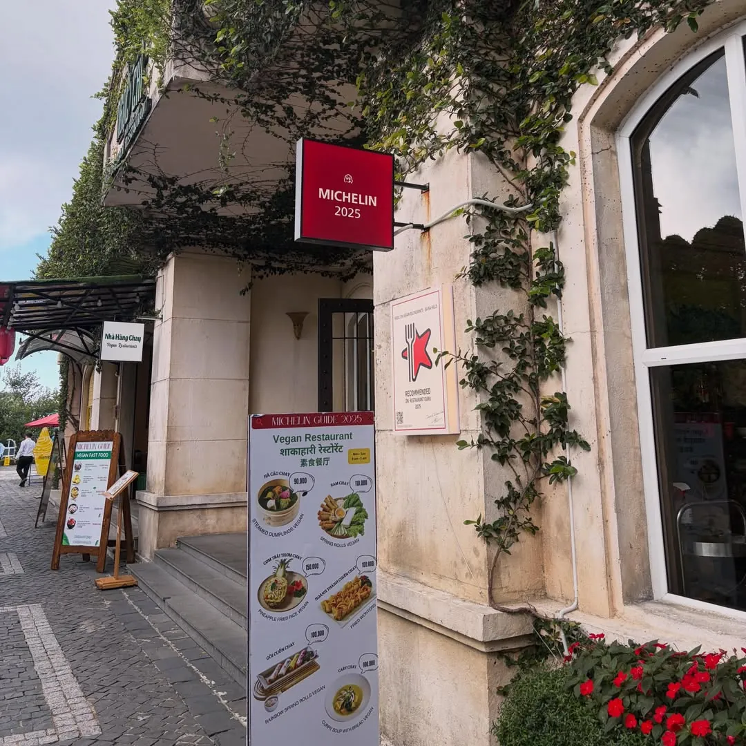 Ngoc Chi Vegetarian Restaurant entrance at Ba Na Hills with Michelin Guide 2025 recognition sign and vegan menu board showing dishes from 90,000 VND