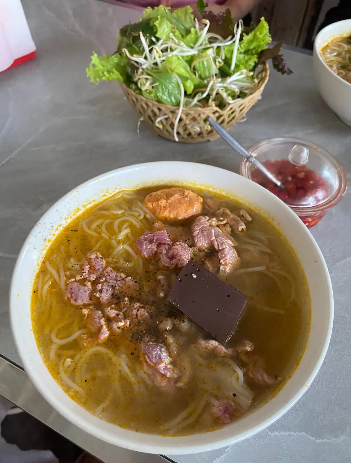 Bun bo Hue served with fresh herbs during a lunch stop in Hue