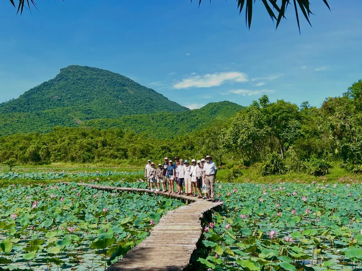Group walking through the lotus pond area inside My Son Sanctuary during a half-day visit