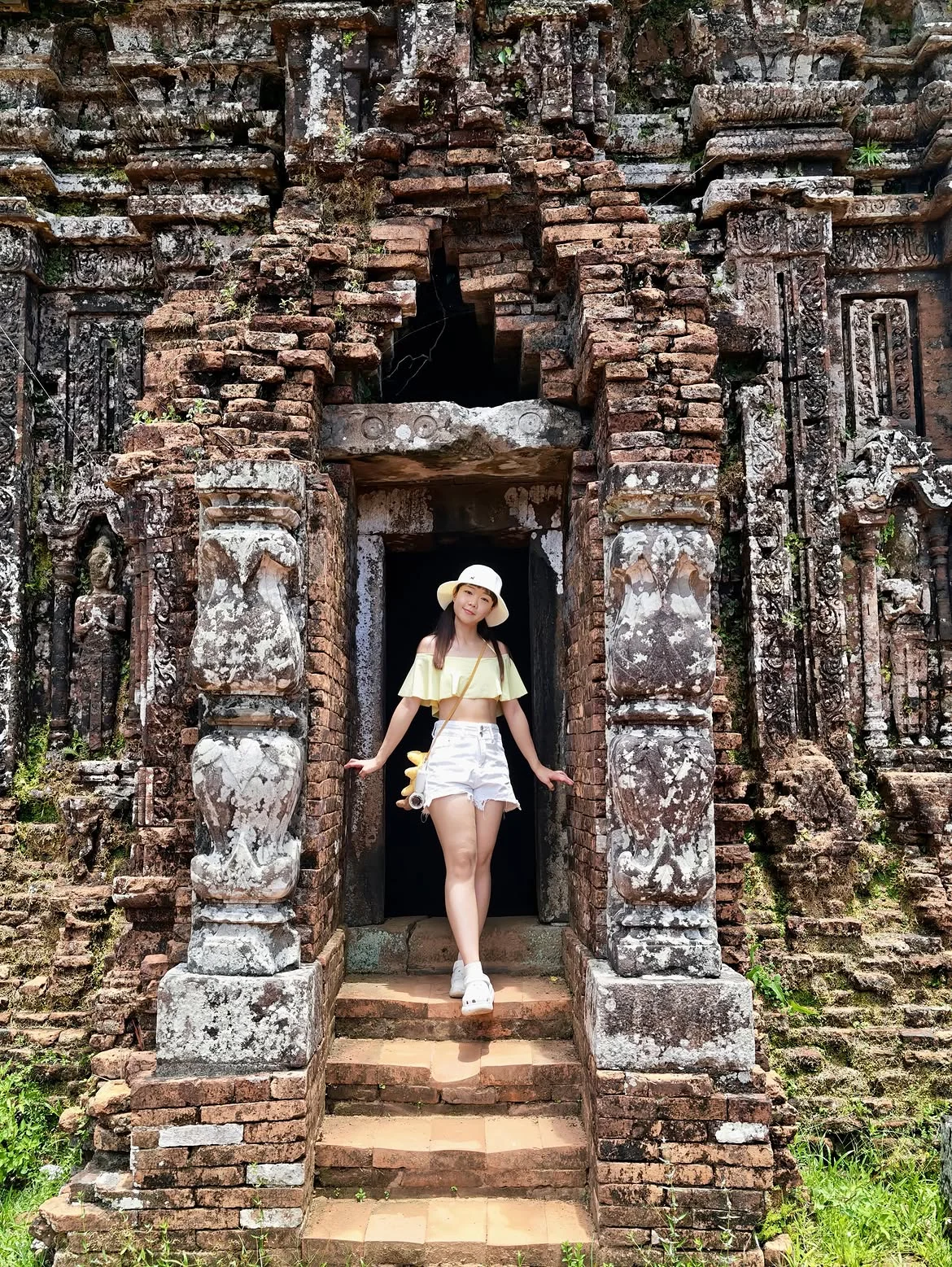 Traveller taking photos at a Cham temple doorway in My Son Sanctuary before the midday heat